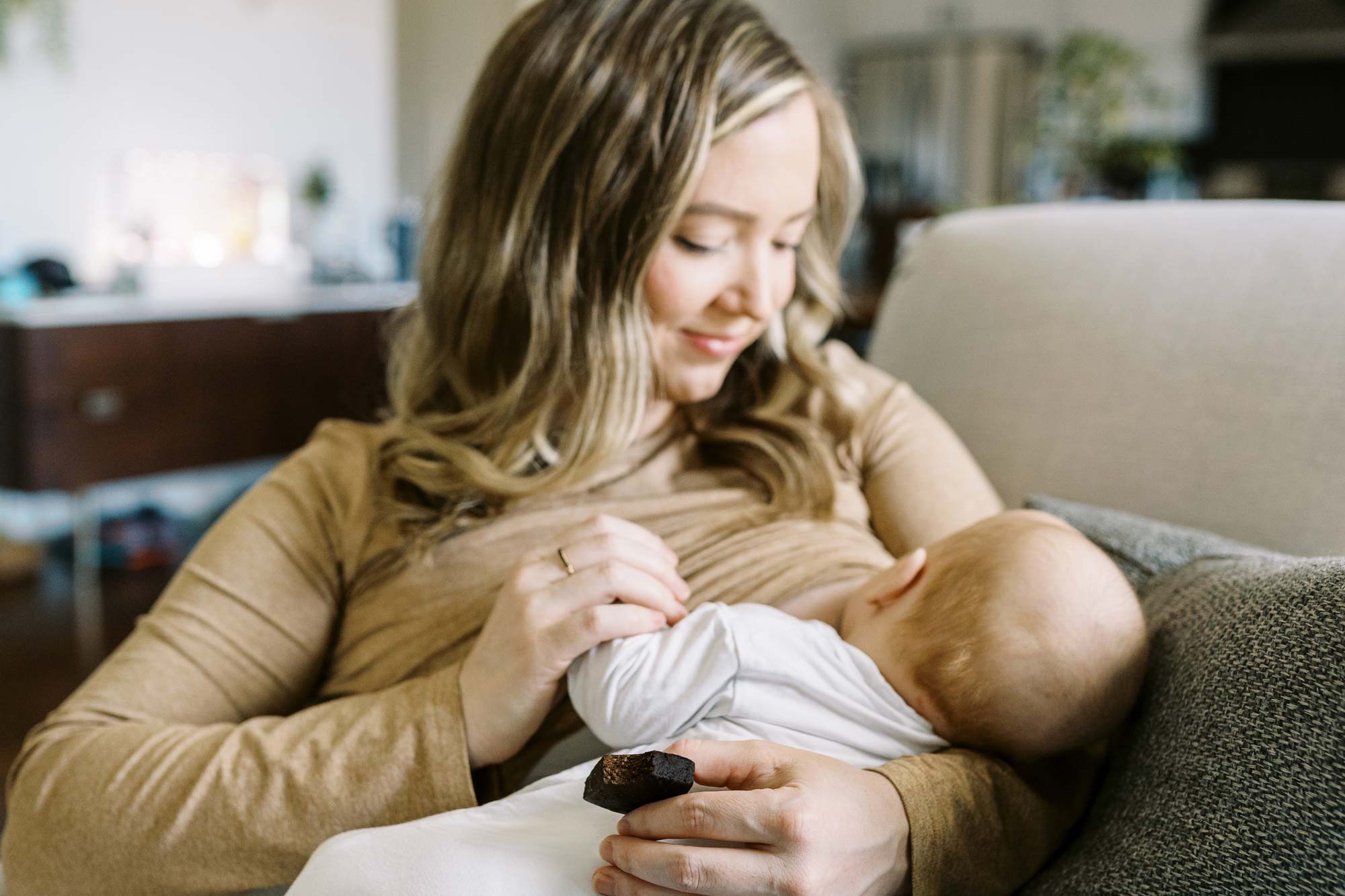 Parent cradling infant while holding Chocolate Sea Salt Lactation Bite