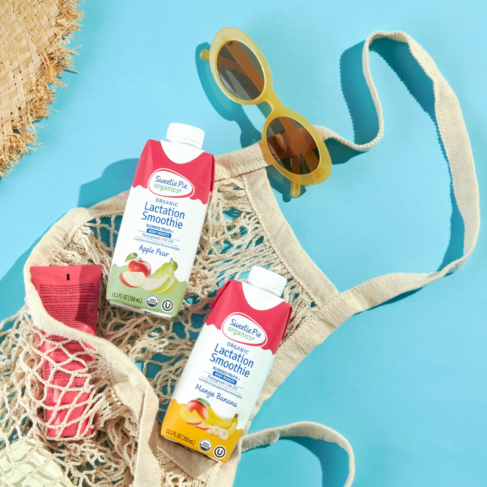 Flatlay image of Sweetie Pie Organics Mango Banana and Apple Bear Smoothie in a beach bag with sunglasses 