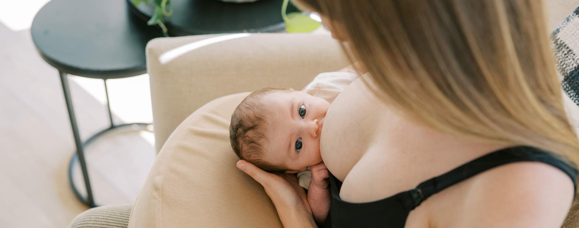 Mother breastfeeding infant while sitting on chair