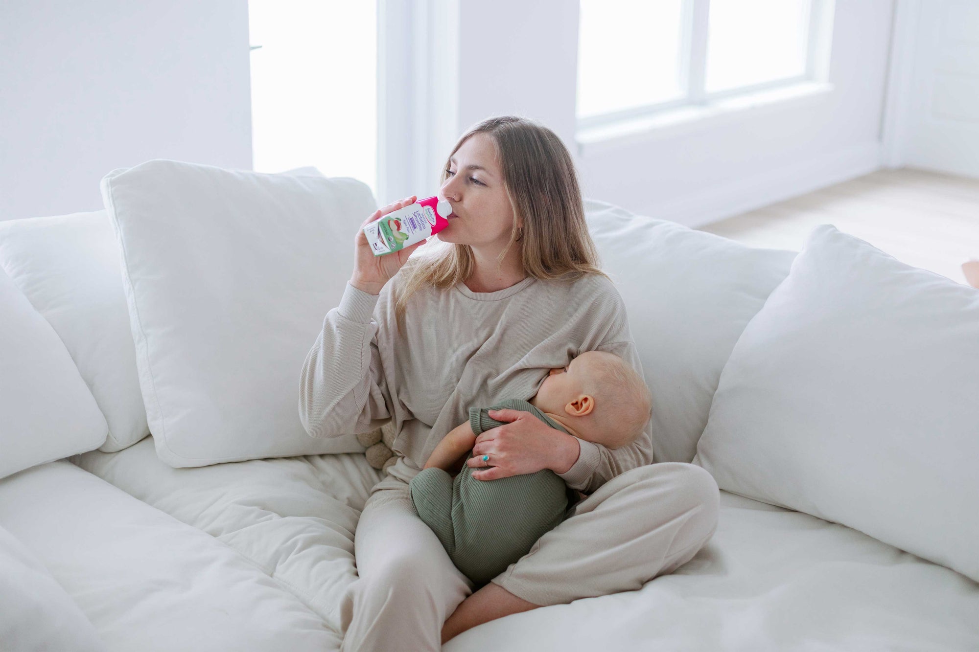 Parent drinking lactation smoothie while holding infant