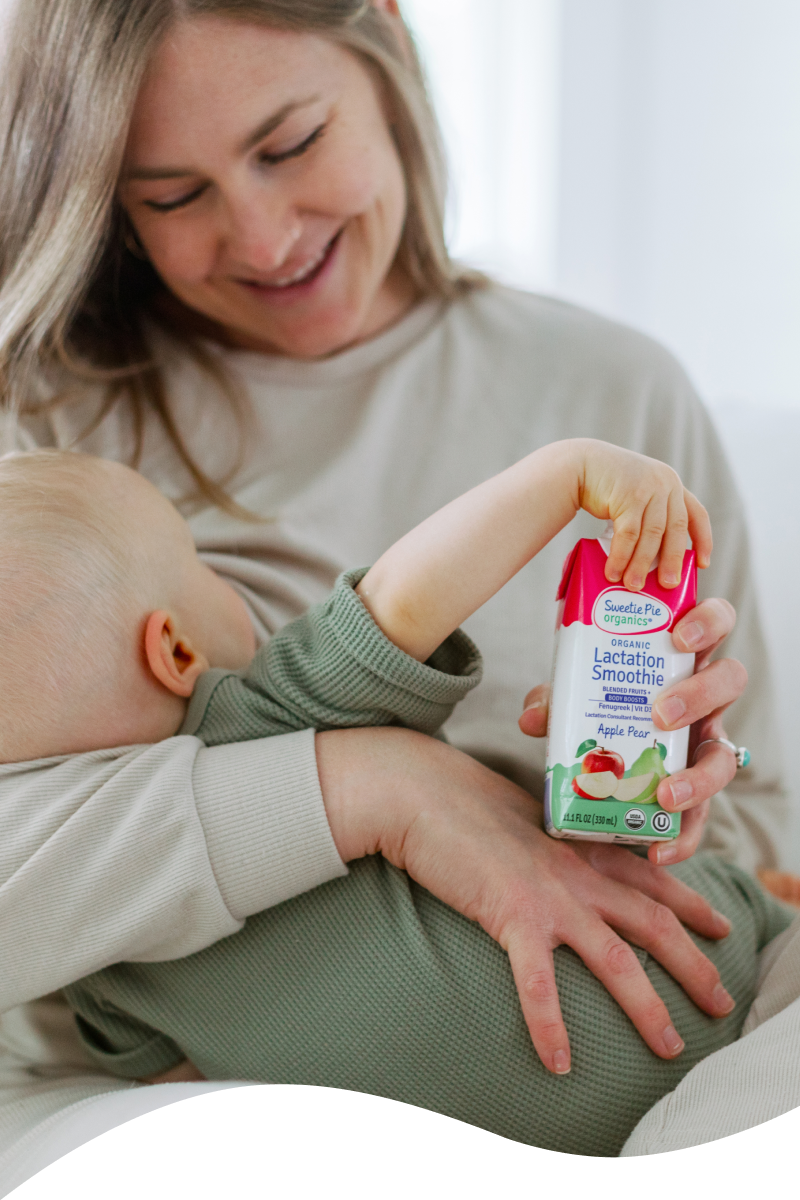 Image of mom breastfeeding her baby holding the apple pear lactation smoothie 